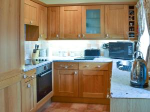 a kitchen with wooden cabinets and a stove at Swallows Nest-18094 in Cloughton