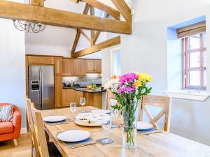 a kitchen with a wooden table with a vase of flowers at Low Barn in Market Bosworth