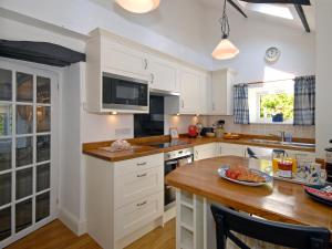 a kitchen with white cabinets and a wooden counter top at Llys Isaf in Saint Nicholas