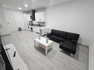 a living room with a black couch and a table at Apartamento mi currilla in Sanlúcar de Barrameda