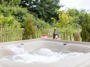 a hot tub with a bottle of wine and glasses at Olive in Wootton Bridge
