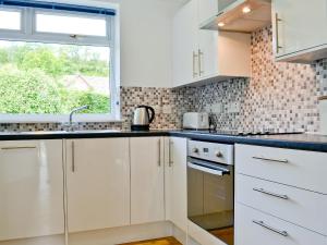 a kitchen with white cabinets and a window at Lunga - 28791 in Clachan