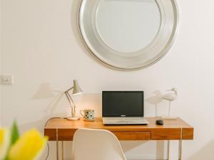 a laptop computer sitting on a wooden desk with a mirror at 50 Bredon Court in Newquay
