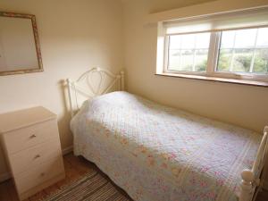 a bedroom with a bed with a dresser and a window at Riffli - Hw7700 in Abersoch +4 photos