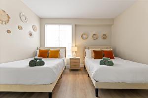 zwei Einzelbetten in einem Schlafzimmer mit weißen und orangefarbenen Kissen in der Unterkunft Great 2bd 2bath in MdR! Free parking and pool! in Los Angeles