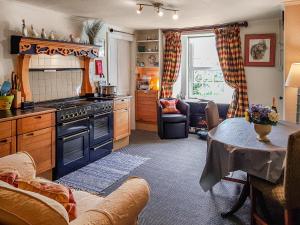 eine Küche mit einem Herd und einem Tisch im Zimmer in der Unterkunft Ivy Cottage in Crieff