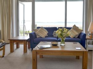 un soggiorno con un divano blu e un tavolo con fiori di West Lawn a Rhosneigr