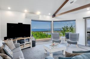a living room with a large tv and a large window at Pure Indulgence in Merimbula