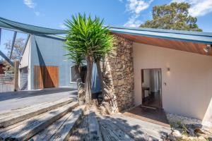 a house with a stone wall and two palm trees at Pure Indulgence in Merimbula