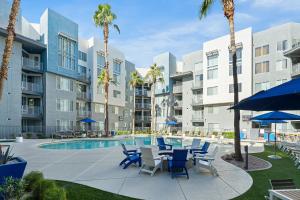 einen Innenhof mit Stühlen und einen Pool mit Palmen in der Unterkunft Modern Tempe Retreat Near ASU & Downtown in Tempe