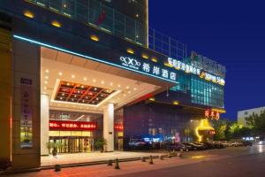 een groot gebouw met 's nachts een bord bij Xana Hotelle Zhengzhou Guoji Branch in Zhengzhou