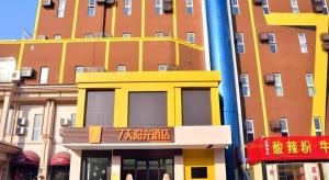 een geel gebouw voor een hoog gebouw bij 7 Days Inn Tai'an Dongpingxi Hualian in Dongping