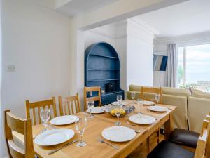 ein Esszimmer mit einem Holztisch mit Tellern und Weingläsern in der Unterkunft On The Beach, East Yardley House - Uk31203 in Downderry