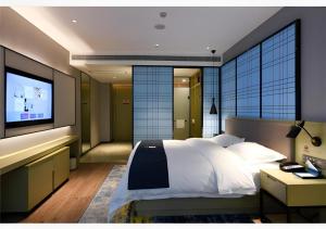 een slaapkamer met een groot bed en een flatscreen-tv bij Echarm Hotel Huaihua Vocational College in Huaihua