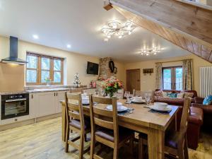 a kitchen and living room with a wooden table and chairs at Farriers Lodge in Burshill +15 photos