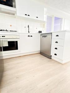 una cucina bianca con armadi bianchi e pavimenti in legno di City Oasis - Free Parking Gym Beach Pool - Sleep 6 a Brisbane