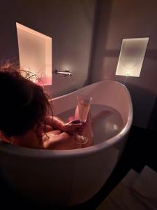 a woman sitting in a bath tub holding a glass at 138 On The Bay - Sunset Bliss on the Waters Edge in Murdunna +60 photos