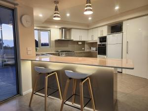 a kitchen with two stools at a kitchen counter at 138 On The Bay - Sunset Bliss on the Waters Edge in Murdunna