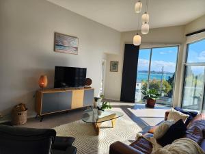 a living room with a tv and a couch and a table at 138 On The Bay - Sunset Bliss on the Waters Edge in Murdunna