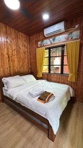 a bedroom with a large bed with yellow curtains at D'Kebun Lenggong Perak Chalet in Gua Sai