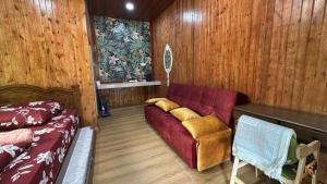 a living room with a red couch and wooden walls at D'Kebun Lenggong Perak Chalet in Kampong Ulu Jepai
