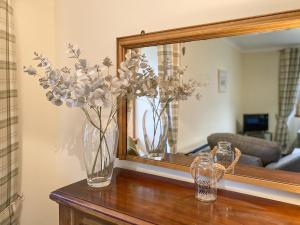 two vases with flowers on a table in front of a mirror at Kirnan Cottage in Kilmichael Glassary