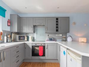 a kitchen with white cabinets and a red towel at Min Y Traeth By The Beach in Morfa Nefyn