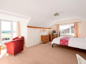 ランズウィックにあるSeacotのベッドと赤い椅子のある寝室