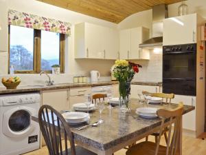 Una cocina con una mesa con sillas y un fregadero. en Woodside Lodge - Hw7520, en Penybont