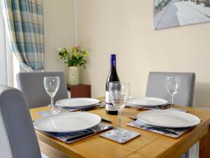 a wooden table with white plates and a bottle of wine at Gwynt Y Môr in Tywyn