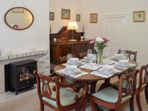 een eetkamer met een tafel met stoelen en een open haard bij Tarn House in Wooler