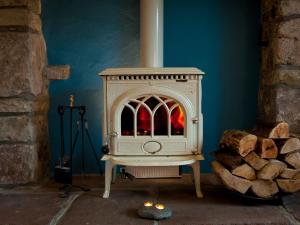 einen weißen Holzofen in einem Zimmer mit Holzscheiten in der Unterkunft Tintern Abbey Cottage in Tintern