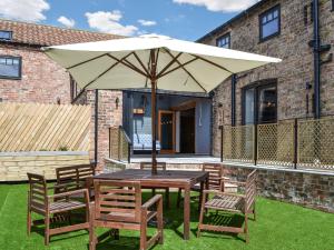 a wooden table and chairs with an umbrella at The Old Stables in Tickton