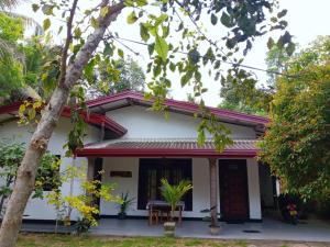 a white house with a red roof at The Onisula Guest House in Ahangama