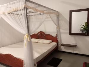 a bedroom with a canopy bed with white curtains at The Onisula Guest House in Ahangama