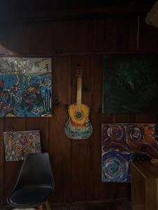 Ein Zimmer mit einer Gitarre und Gemälden an der Wand in der Unterkunft la punta surf house 2 in Brisas de Zicatela