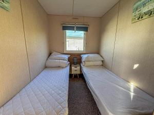 ein kleines Zimmer mit zwei Betten und einem Fenster in der Unterkunft Beautiful 6 Berth Caravan For Hire With Huge Decking At Manor Park Ref 23142K in Hunstanton + 14 Fotos