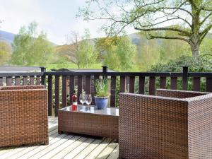 two wicker chairs and a table on a deck at Fell View Lodge in Keswick +2 photos