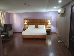 - une chambre avec un lit, une chaise et deux lampes dans l'établissement Li Tour International Hotel, à Ikeja