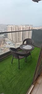 d'une table et d'une chaise sur un balcon offrant une vue sur la ville. dans l'établissement Blue Sapphire Forest Stays, à Ghaziabad