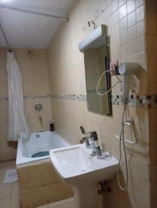 une salle de bains avec lavabo et baignoire dans l'établissement Li Tour International Hotel, à Ikeja