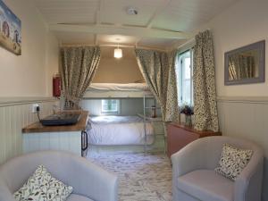 a bedroom with a bed and a desk and two chairs at Honeysuckle Hut-Qu7066 in Melton Constable