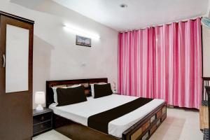 a bedroom with a bed and a pink curtain at Hotel O Basera in Dalhousie