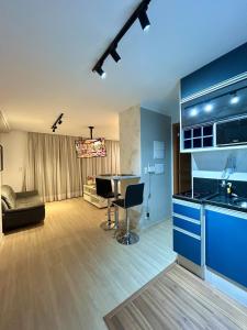 a kitchen and living room with blue cabinets and a table at Studio Sofisticado 2106 - Próx Aeroporto GRU in Guarulhos