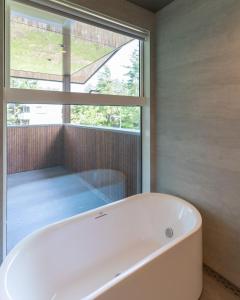 a bath tub in a bathroom with a window at Base 47 Hakuba by Jade Group in Hakuba +38 photos