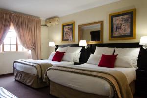 two beds in a hotel room with red pillows at Nelspruit Lodge in Nelspruit +154 photos
