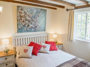 Un dormitorio con una cama con almohadas rojas y blancas. en East Granary - 28956, en Eye