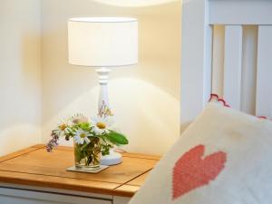 una lámpara en una mesa con un jarrón de flores en East Granary - 28956, en Eye 9 fotos más