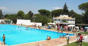 a large swimming pool with many people in it at Casa San Rafael, magnífico chalet con gran jardín in Navajas