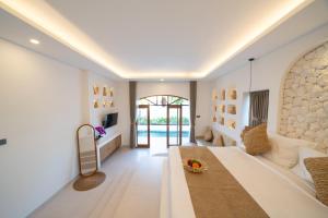 a bedroom with a large bed and a living room at Dianatara Villa by Dhananjaya Hospitality in Sukawati